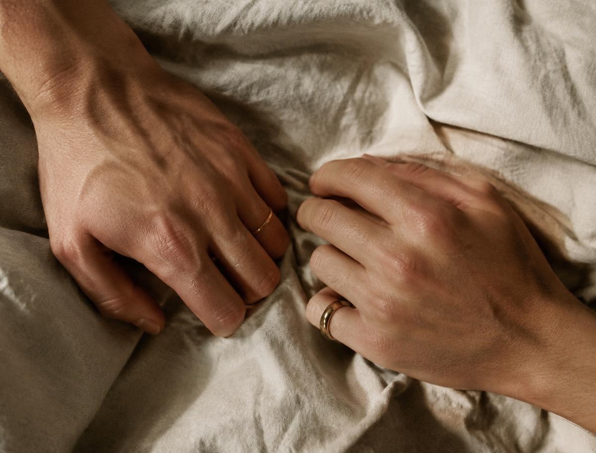 Deux mains posées sur un drap de lin froissé, proches sans se toucher