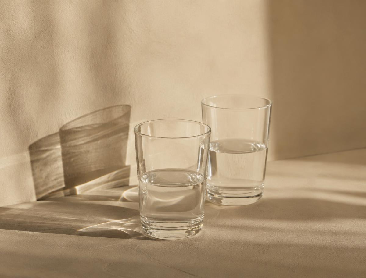 Deux verres d'eau dont les ombres se croisent sur un mur clair
